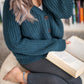 Nui Organics Women's Bernard Cardigan in Deep Sea — overhead view of woman in teal chunky merino cardigan seated cross-legged reading a book