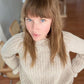 Nui Organics Women's Fishline Sweater in Oatmeal — overhead view of woman in chunky oatmeal merino sweater with white jeans indoors