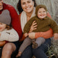 Nui Organics Women's Knit Leggings in Charcoal — woman wearing charcoal rib knit merino leggings seated with family in coastal dunes