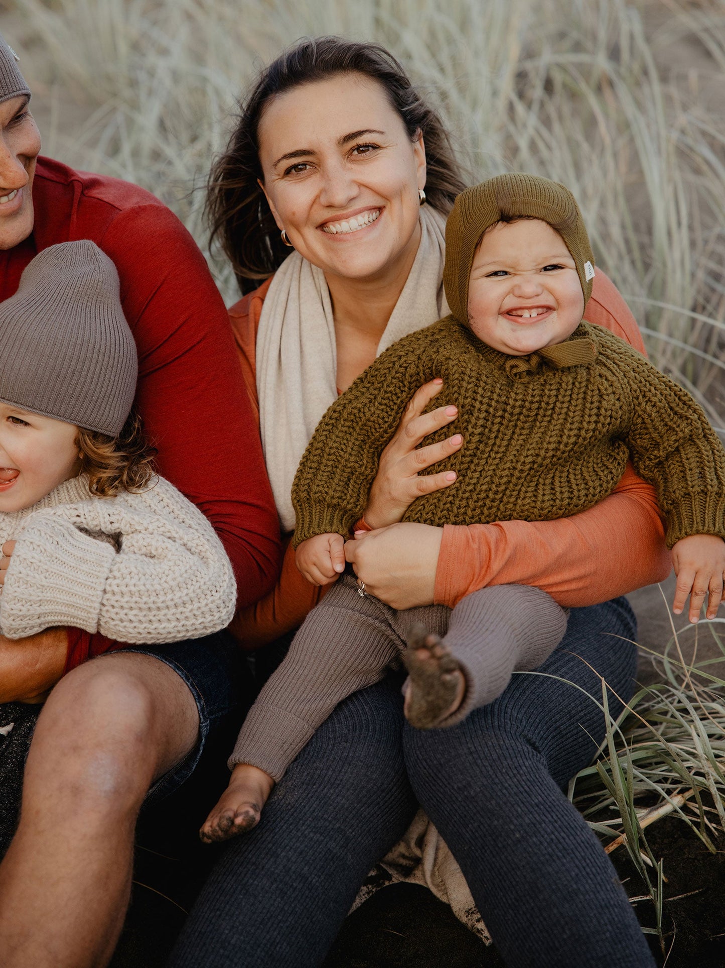 Nui Organics Women's Knit Leggings in Charcoal — woman wearing charcoal rib knit merino leggings seated with family in coastal dunes