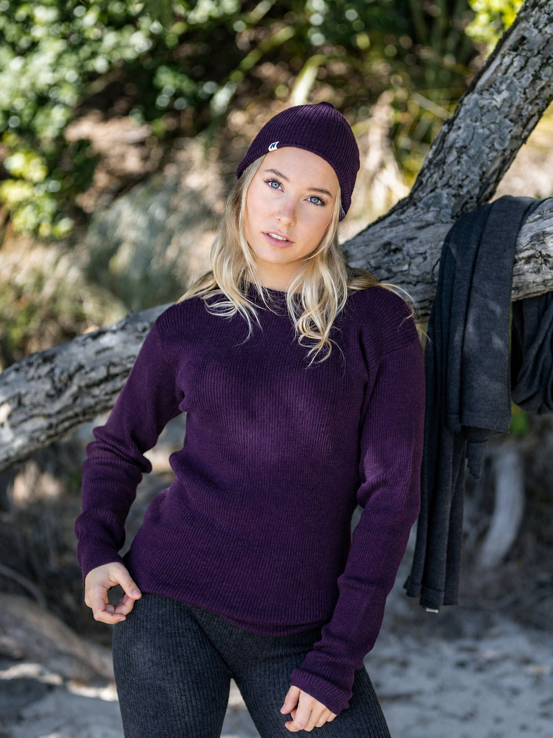 Nui Organics Women's Hopu Top in Plum — woman in plum rib knit merino top and beanie with charcoal leggings outdoors by a tree