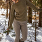Nui Organics Women's Knit Leggings in Sparrow — woman in sparrow rib knit merino leggings and olive sweater walking through a snowy forest.