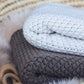 Nui Organics Koha Merino Baby Blanket - two textured knit merino wool blankets in Oatmeal and Cocoa folded in a wicker basket.