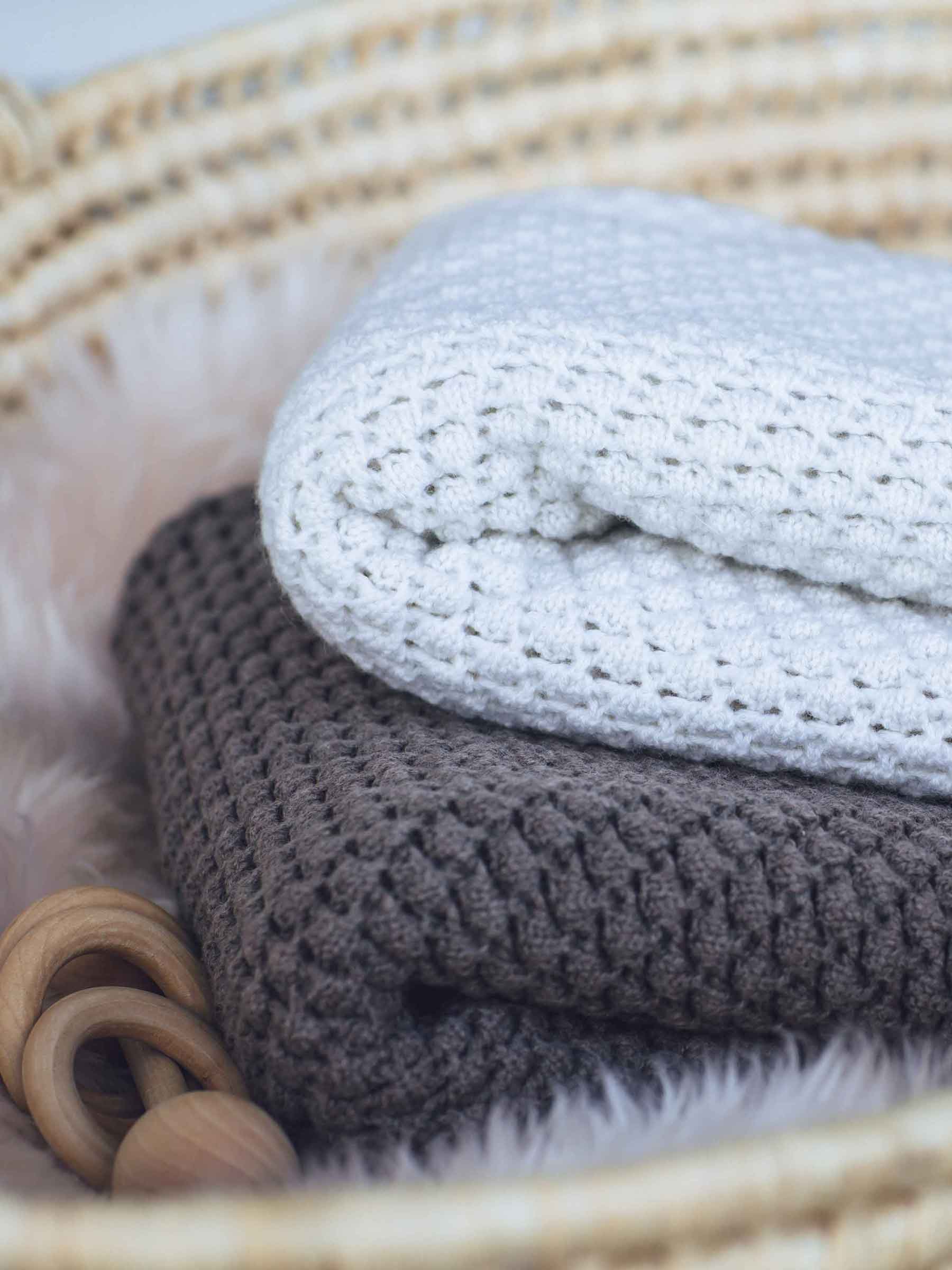 Nui Organics Koha Merino Baby Blanket - two textured knit merino wool blankets in Oatmeal and Cocoa folded in a wicker basket.