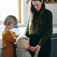 Nui Organics Women's Fishline Sweater in Kelp — woman in chunky olive merino knit sweater with two young children in a home kitchen