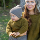 Nui Organics Women's Fishline Sweater in Kelp — mother and baby wearing matching chunky olive merino knit sweaters and grey beanies outdoors