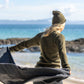 Nui Organics Women's Knit Leggings in Charcoal — rear view of woman in charcoal rib knit merino leggings and olive top holding a wrap on a breezy beach